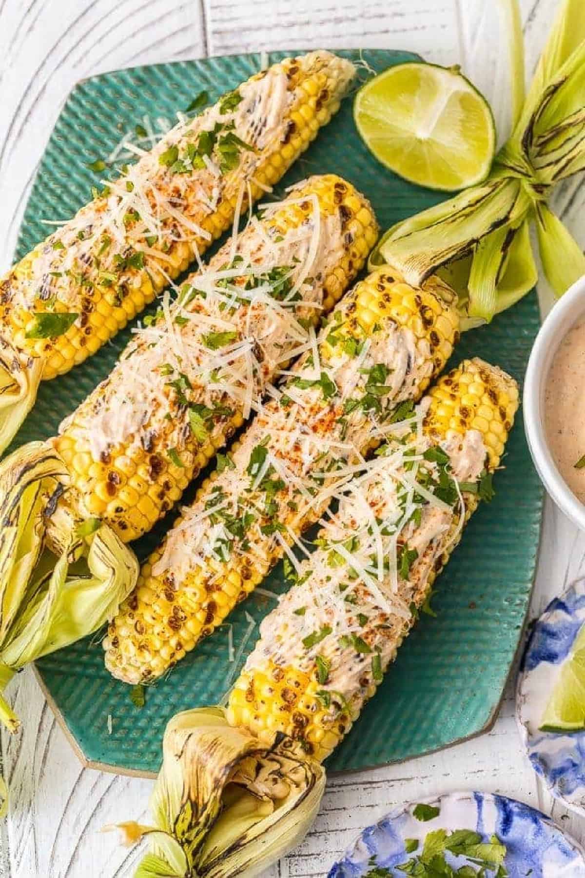 Mexican Grilled Corn on the Cob is the perfect Summer side dish! We love to make this Mexican Corn on the Cob recipe and serve it all summer long. This Mexican Corn recipe is so easy, unique, flavorful and delicious! It's the perfect Mexican corn side dish for every occasion. mexican grilled corn on a green platter