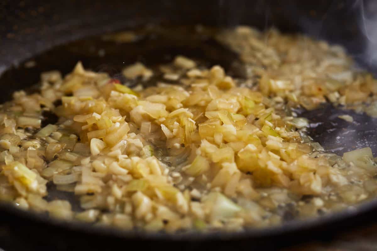 diced onions and garlic cooking in a pan.
